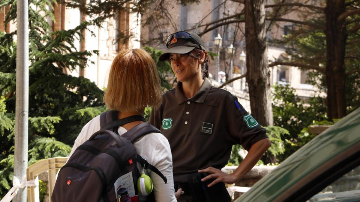 Una agente de los Agentes Rurales explica a una turista que no puede acceder por el Camino de Sant Miquel.