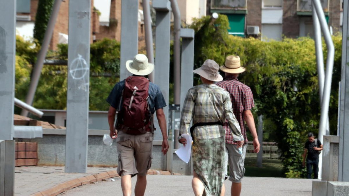 Plano abierto con tres turistas con la cabeza cubierta con sombreros en Lleida.