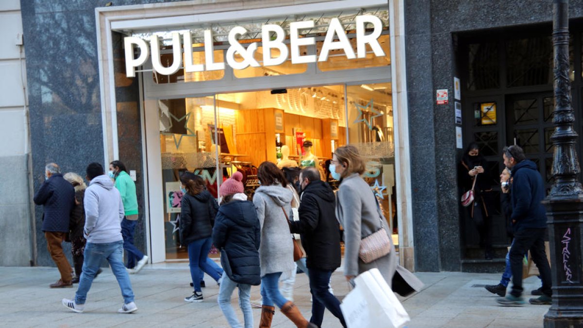 Compradors passen per davant d'una botiga Pull & Bear a Barcelona.