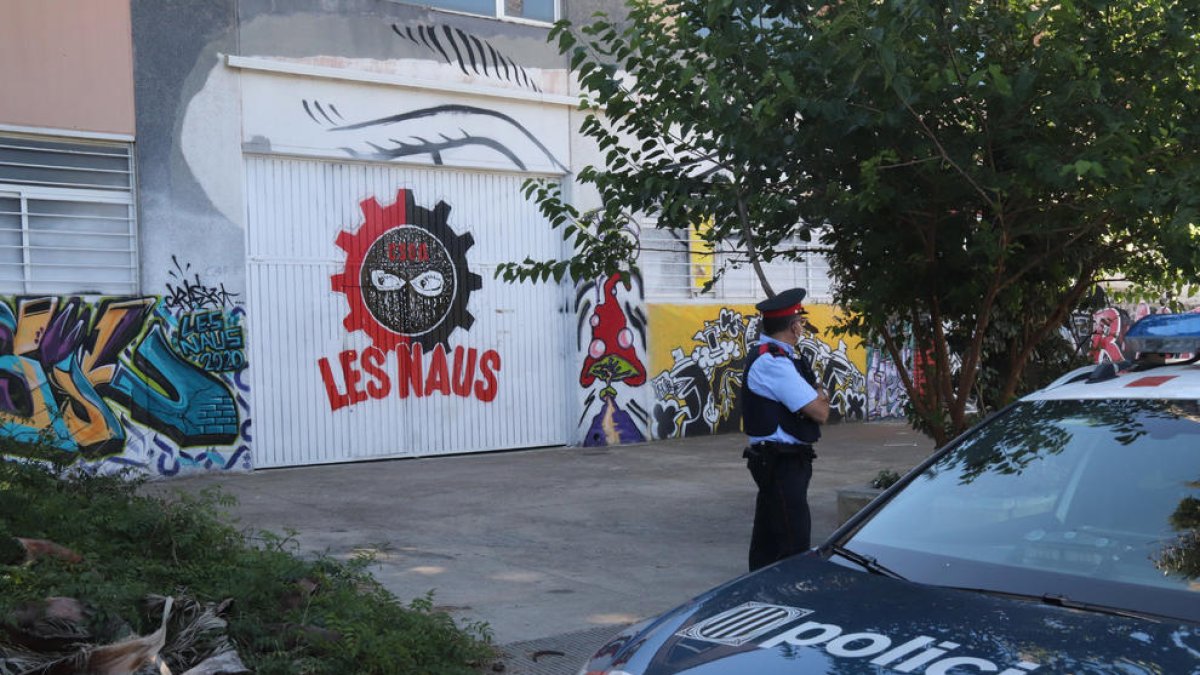 Plano general de la puerta principal del CSOA Les Naus de Torredembarra, vigilada por un agente de los Mossos d'Esquadra.