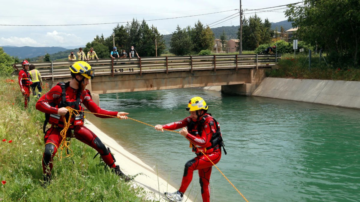 Dos bomberos haciendo prácticas de rescate acuático en el canal de Gavet. Un bombero estira con una cuerda a otro que simulaba haber caído.