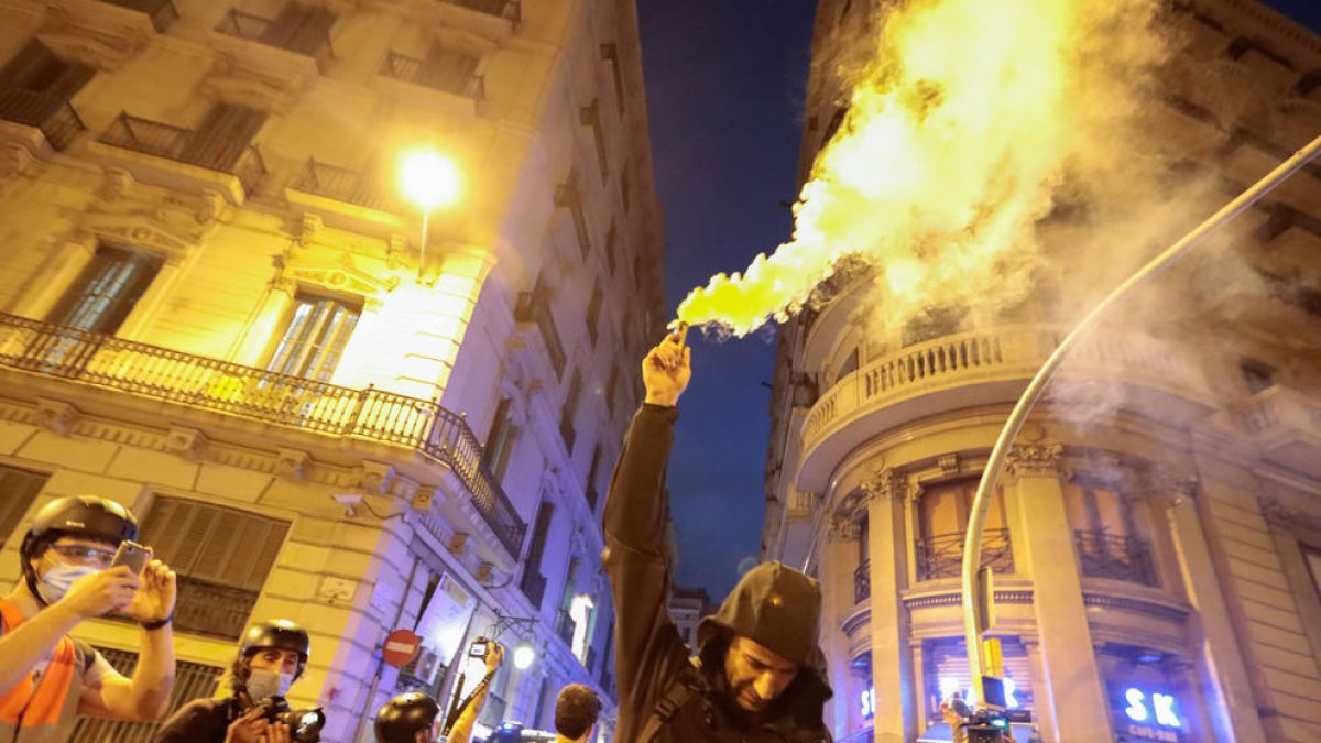 Un hombre con capucha sujeta una bengala en la vía Laietana de Barcelona el 11 de septiembre del 2021.