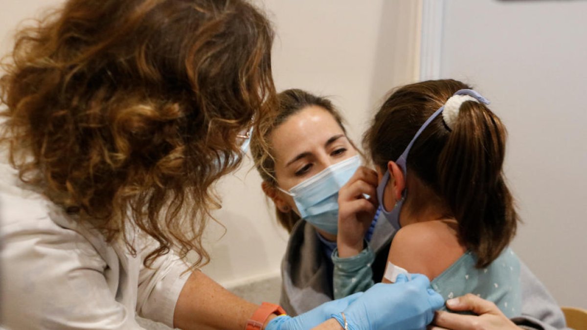 Una infermera posant la tireta a una nena després de posar-li la vacuna.