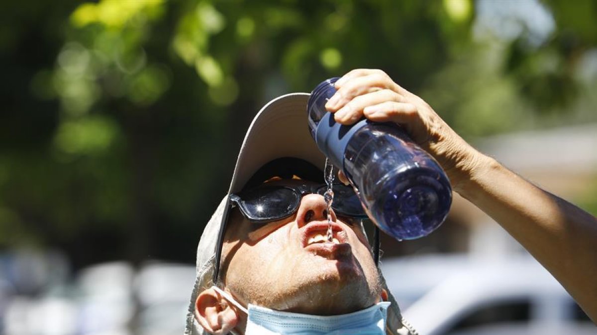 Iatge de archivo de un joven bebiendo agua en la calle.