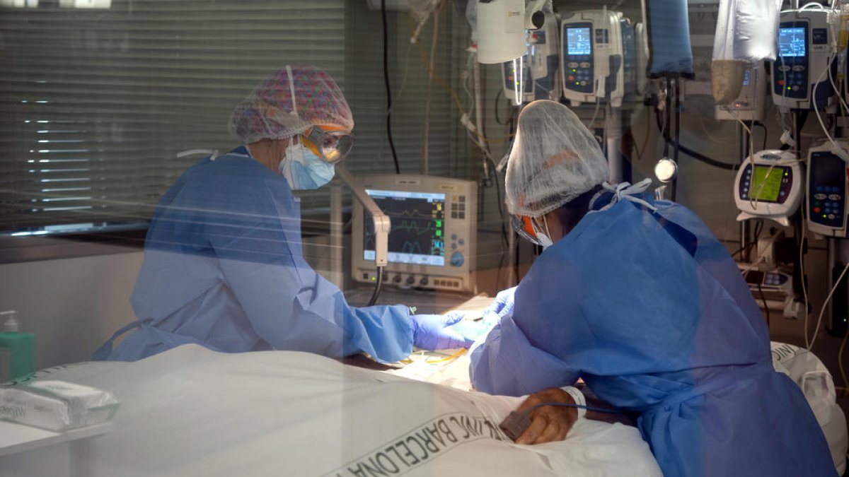 Dos profesionales sanitarias del Hospital Clínico con un paciente ingresado en el Área de Vigilancia Intensiva (ABUELO, o UCI), durante la quinta ola|oleada de la pandemia de la covid-19 en Cataluña.