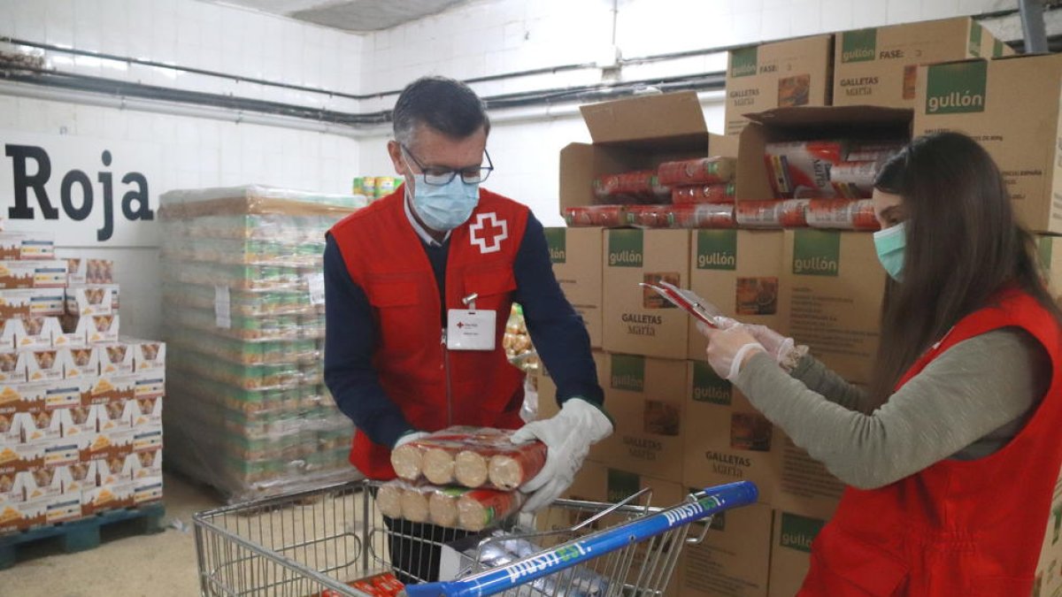 Dos voluntarios de Cruz Roja Tarragona llenando el carro de alimentos para|por una persona en situación de vulnerabilidad.