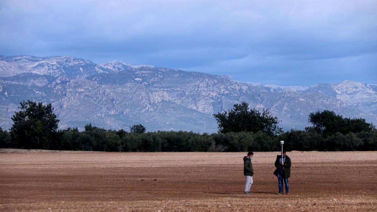 Els terrenys on es projecta la planta de compostatge a Santa Bàrbara amb dos persones prenent mesures.