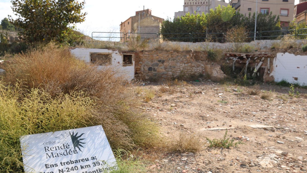 Solar y restos de escombros a raíz de|junto a río en l'Espluga de Francolí donde destaca el mensaje de los propietarios de una bodega destruida, comunicando la nueva ubicación.