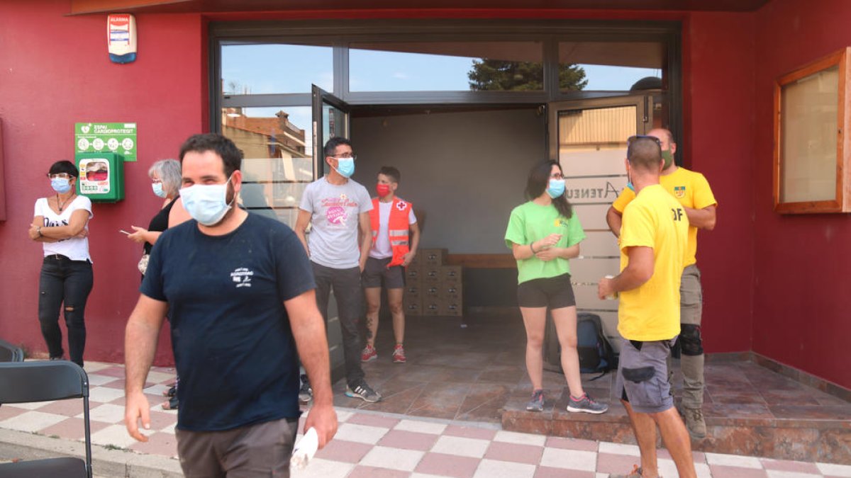 Los voluntarios en la entrada del Ateneu de Sant Martí de Tous que participan en las tareas para apagar el fuego que crema en las comarcas de la Conca de Barberà y la Anoia.
