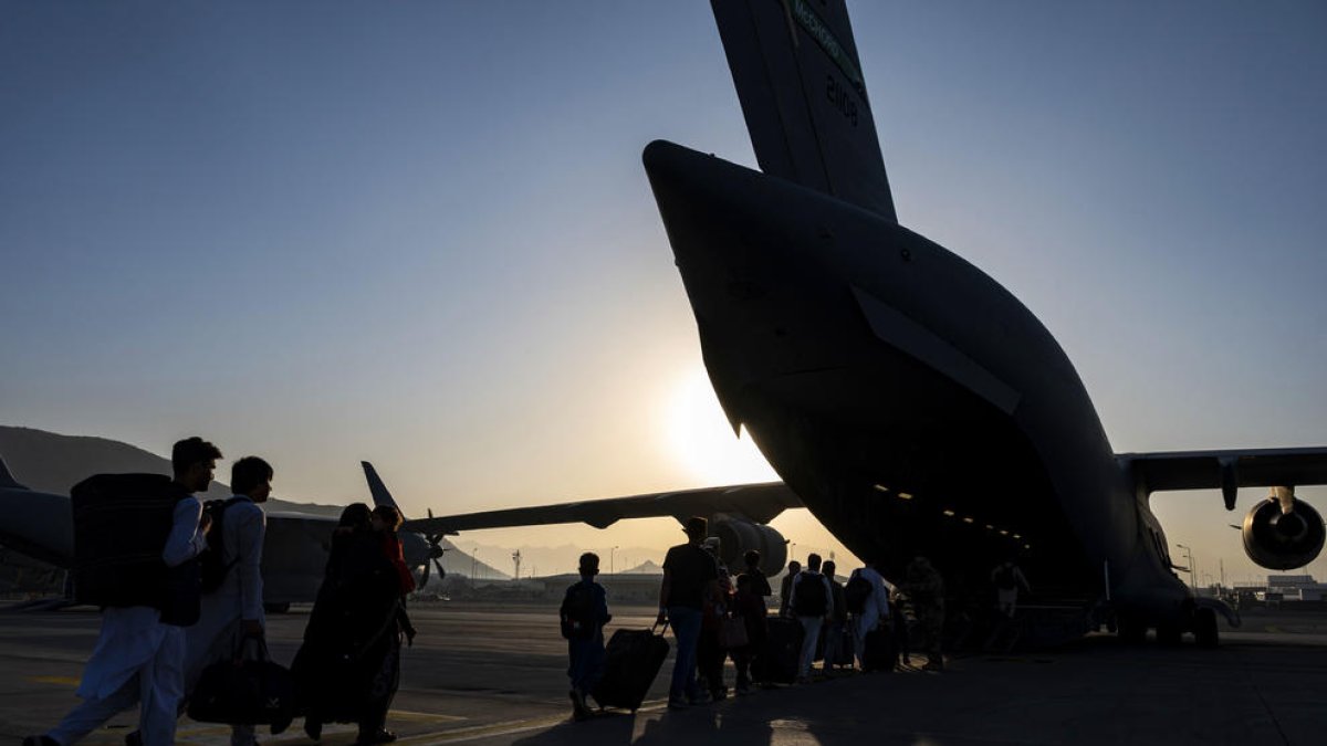 Un grupo de afganos se acerca a un avión del ejército de los Estados Unidos, en el aeropuerto de Kabul, para ser evacuados.