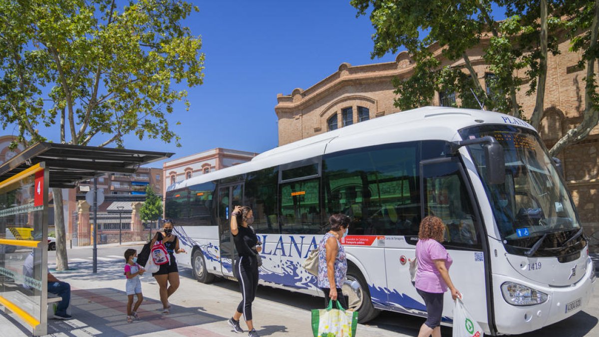 Usuarios del transporte público esperando para subir al autobús en la parada Reus Centro (Paseo)