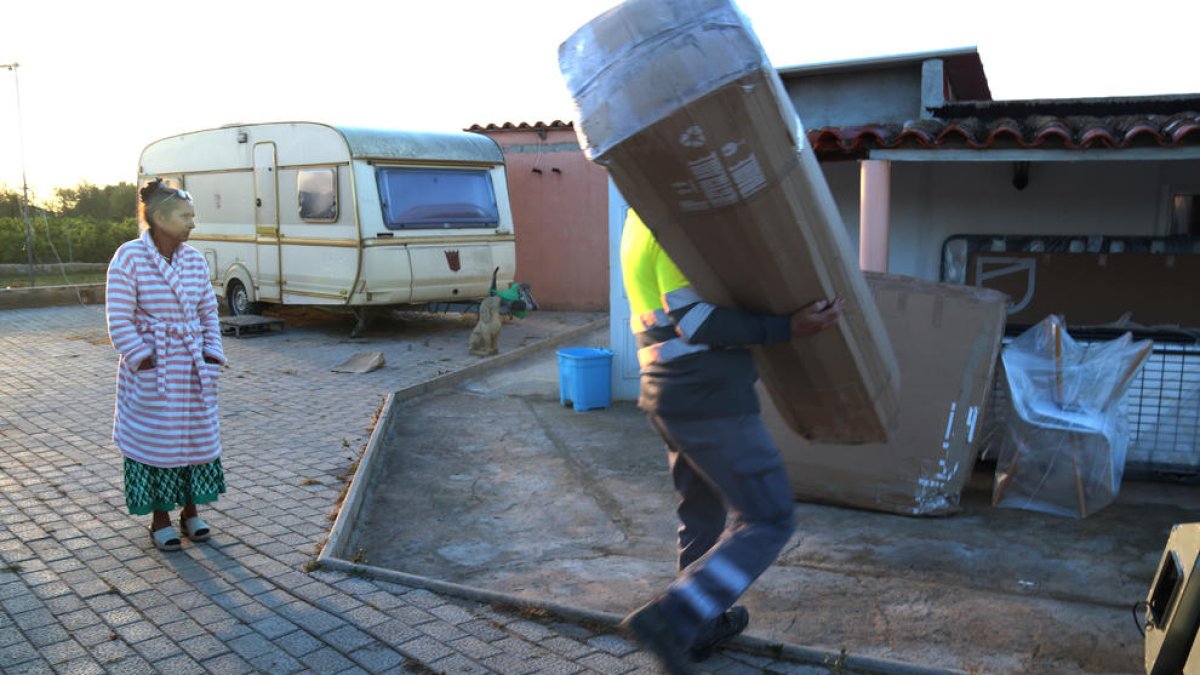 La Milka Gordievic ante|delante de la caravana donde vive ahora mientras los miembros de la brigada municipal de Alcanar le descargan el lote de muebles que le han dado.