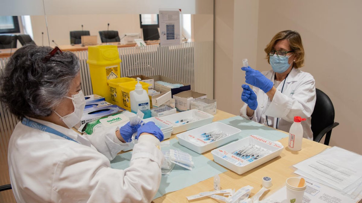 Dues professionals preparen la tercera dosi de la vacuna per a personal de l'Hospital Clínic.