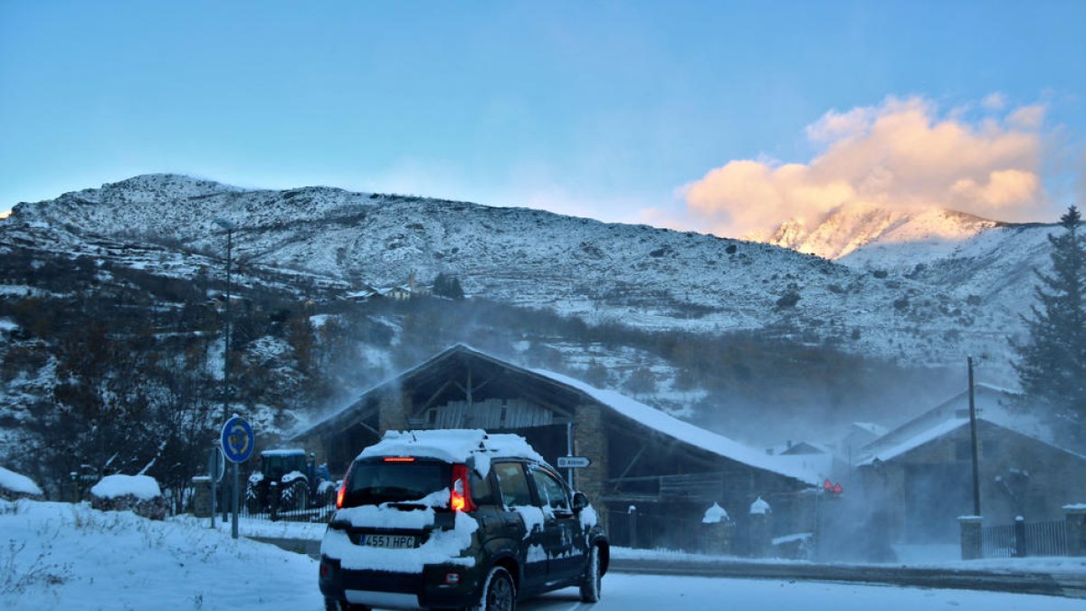 Un coche lleno de nieve circulando por una rotonda.