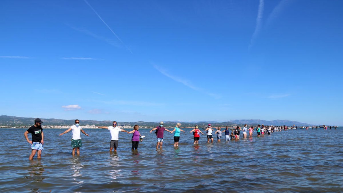 Los participantes haciendo la cadena humana a la bahía del Fangar, en l'Ampolla (Baix Ebre), para denunciar la regresión que sufre el delta del Ebro.