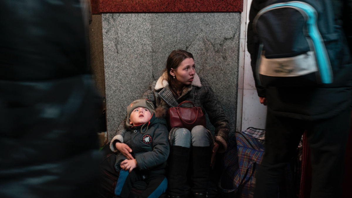 Una mujer y un niño se sientan en la estación de trenes de Lviv durante la invasión militar rusa en Ucrania.