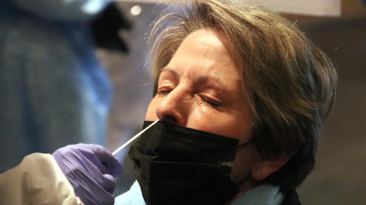 Una mujer con los ojos cerrados mientras le extraen una muestra de PCR.