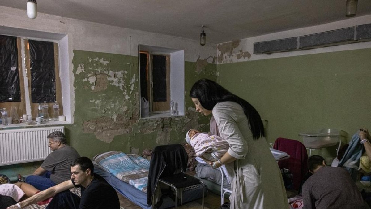 Una madre coge en brazos a su hijo recién nacido en el sótano de un hospital de maternidad, utilizado ahora como refugio antiaéreo en Kiev.