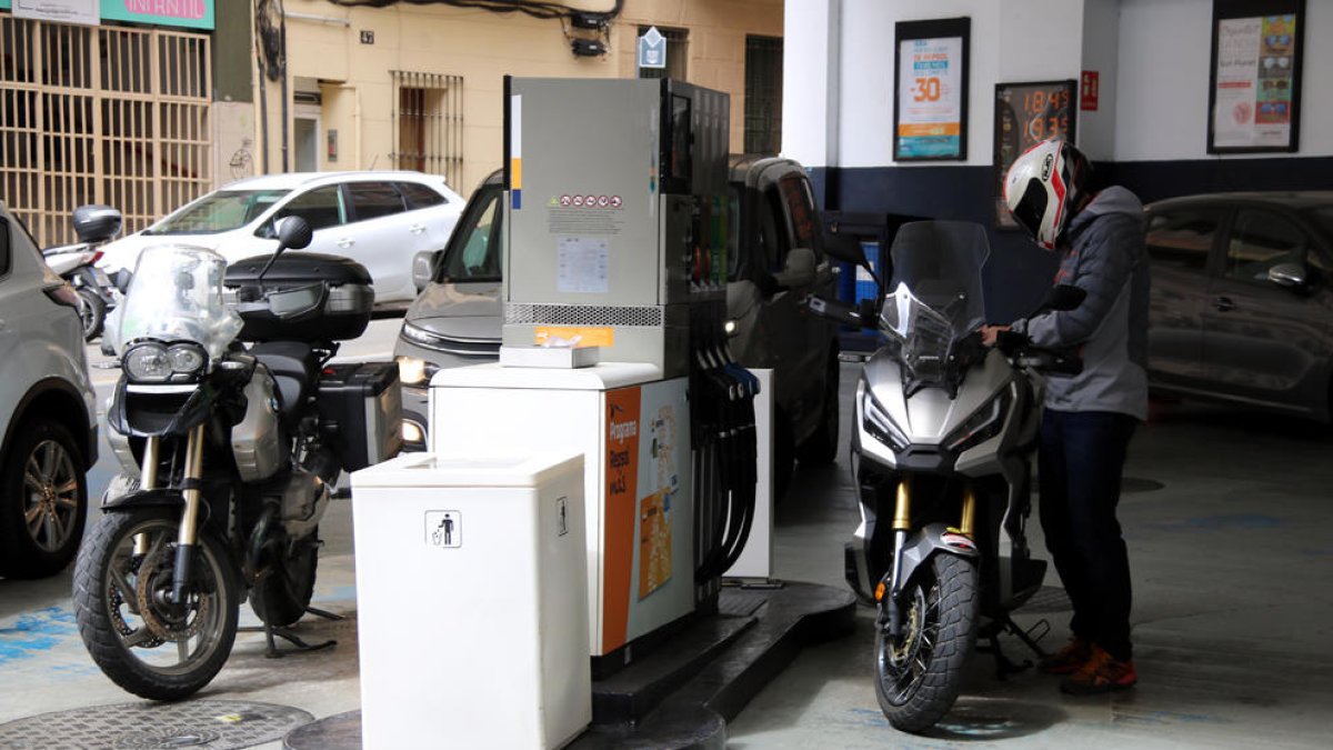 El conductor d'una moto posant combustible a la gasolinera.