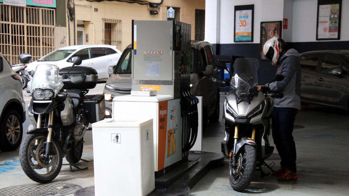 El conductor de una moto poniendo combustible en la gasolinera.