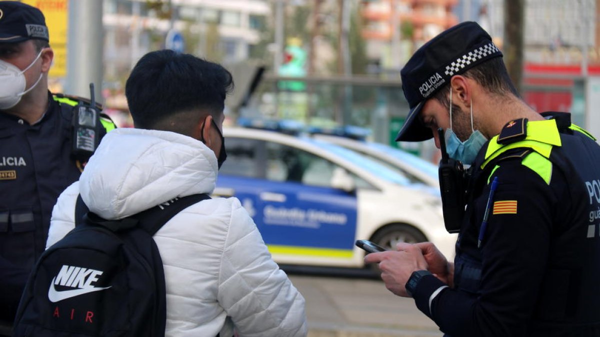 Un usuario de patinete eléctrico, parado durante un control de la Guardia Urbana de Barcelona, ante la Torre Glorias, mientras un agente lo identifica.