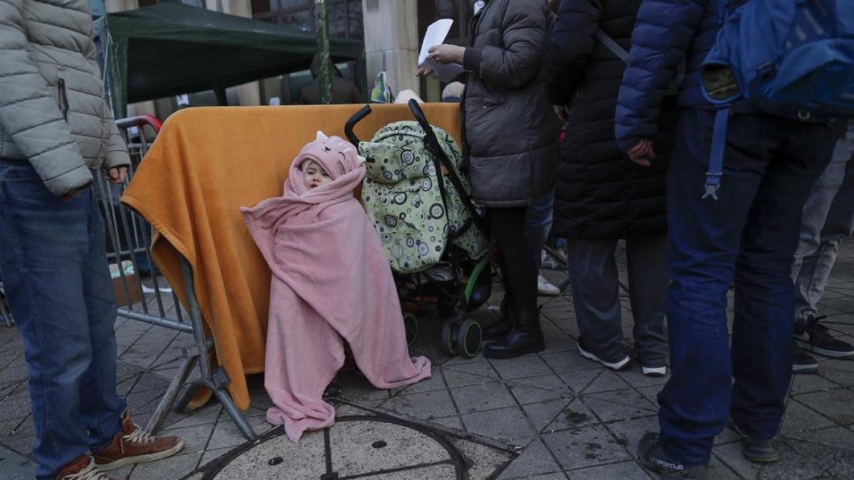 Ucranianos que huyeron de su país en medio de la invasión rusa en curso hacen cola frente a una oficina de inmigración en Bruselas.