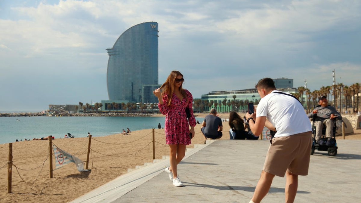 Dos turistas haciéndose una foto con el hotel Vela de fondo.