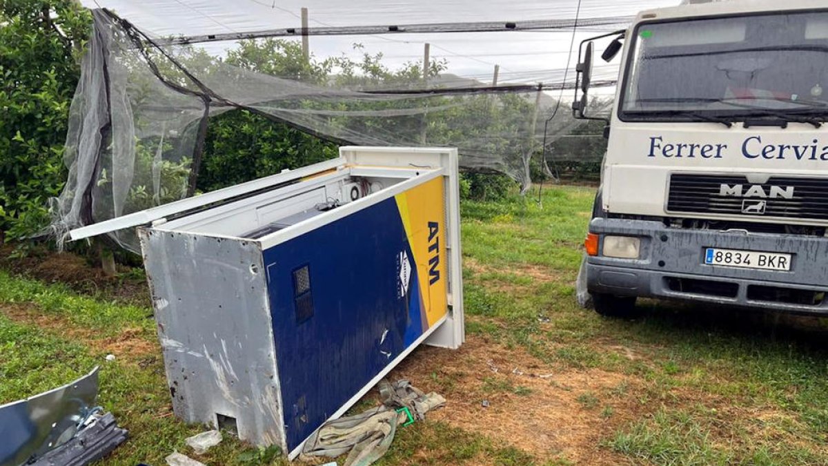 En primer término, el cajero desmontado en piezas; en el fondo, el camión robado abandonado en el campo de manzanos de Torroella de Montgrí.