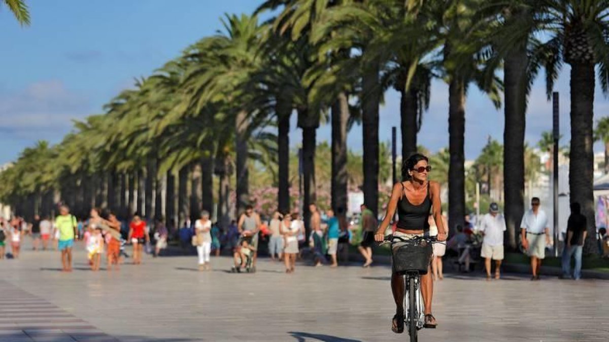 Imagen de una turista en bicicleta por el paseo Jaume I.