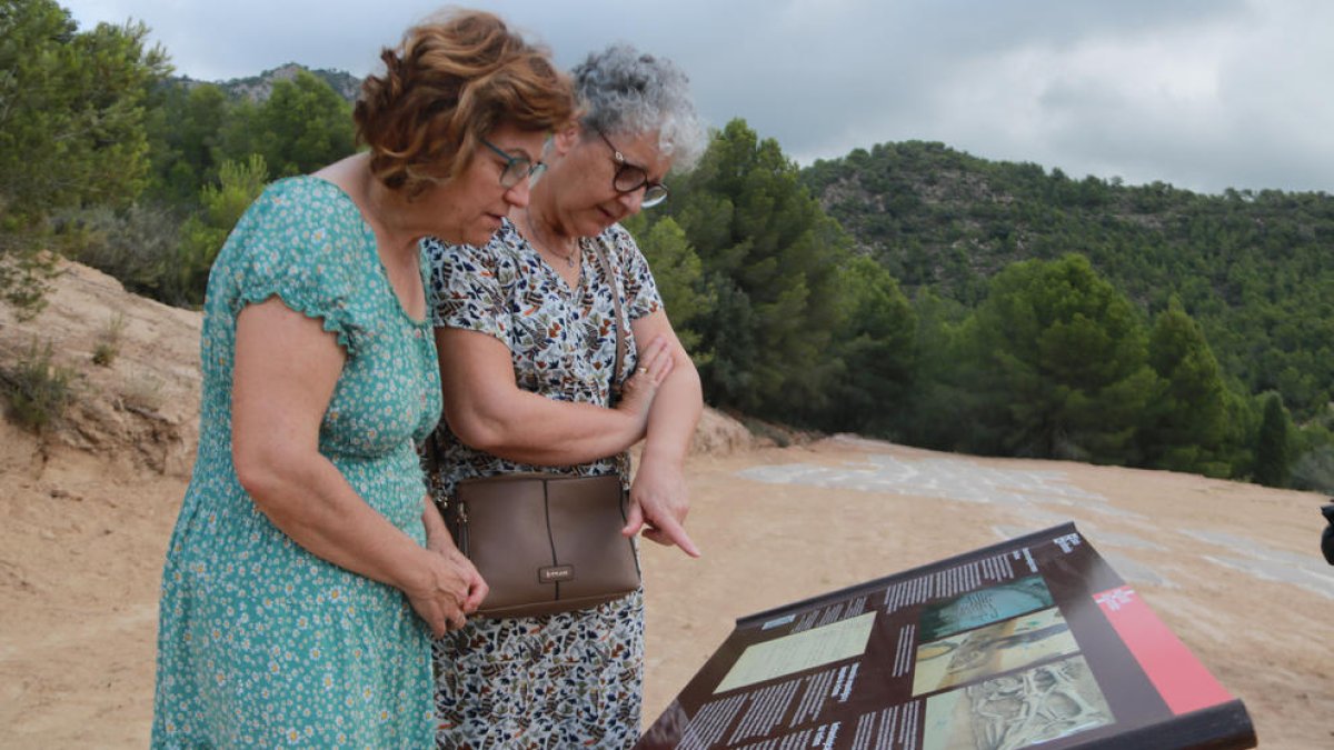 Dos mujeres leen el panel informativo instalado en el Mas de Santa Magdalena, en Móra d'Ebre.