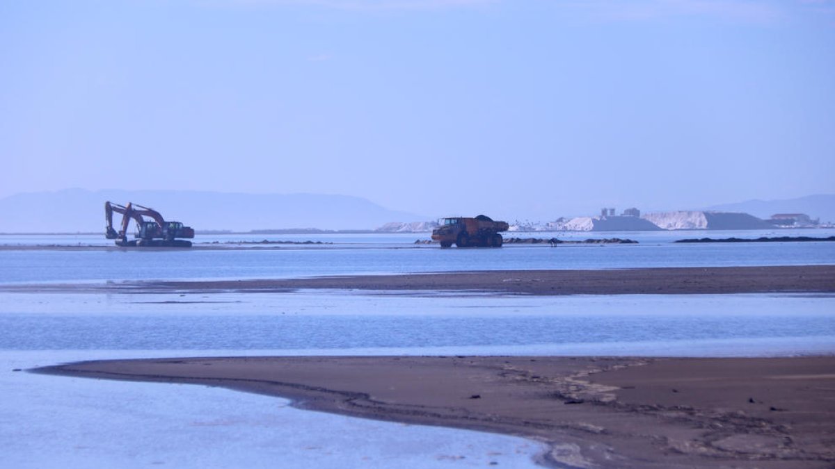 Máquinas trabajando en la barra del Trabucador con las salinas, en el fondo.