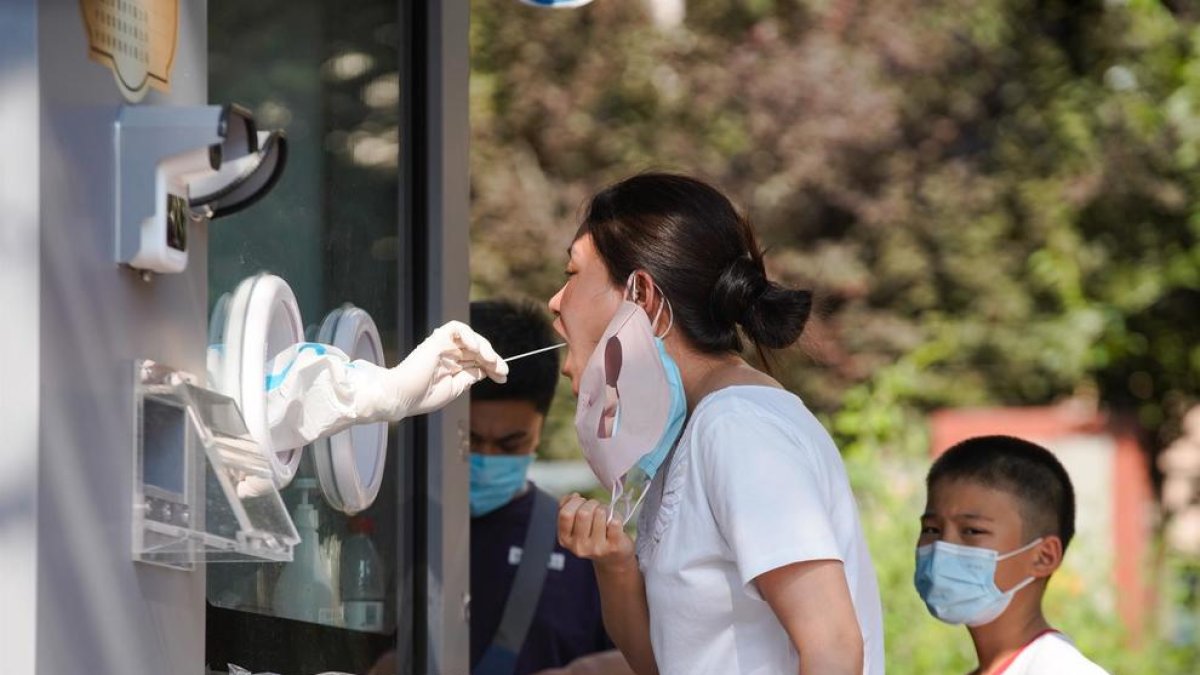 Un sanitario toma una muestra de hisopo de una mujer para hacerle la prueba de covid-19.