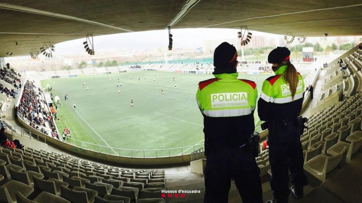 Dos mossos vigilant durant un partit de futbol.