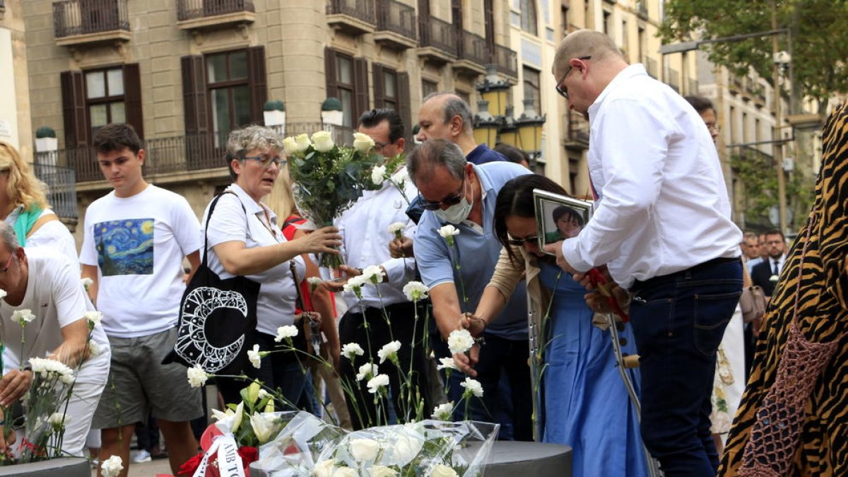 Familiars de les víctimes dels atemptats del 17-A dipositen els clavells blancs al memorial pla de l'Ós de la Rambla.