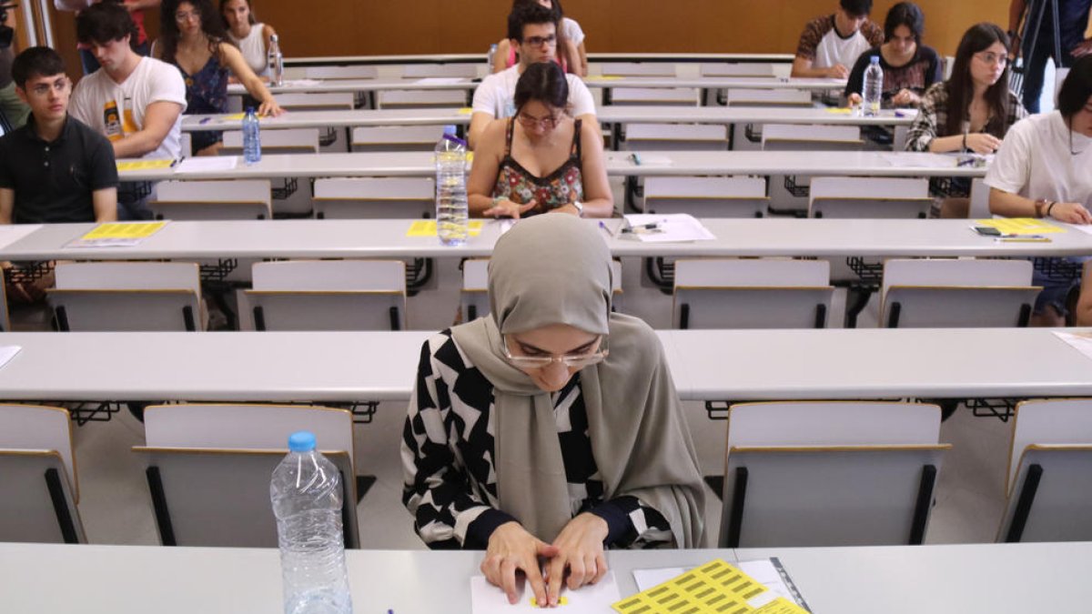 Alumnes enganxen l'etiqueta identificativa abans de començar l'examen de castellà de les PAU, al Campus Catalunya de la URV, a Tarragona.