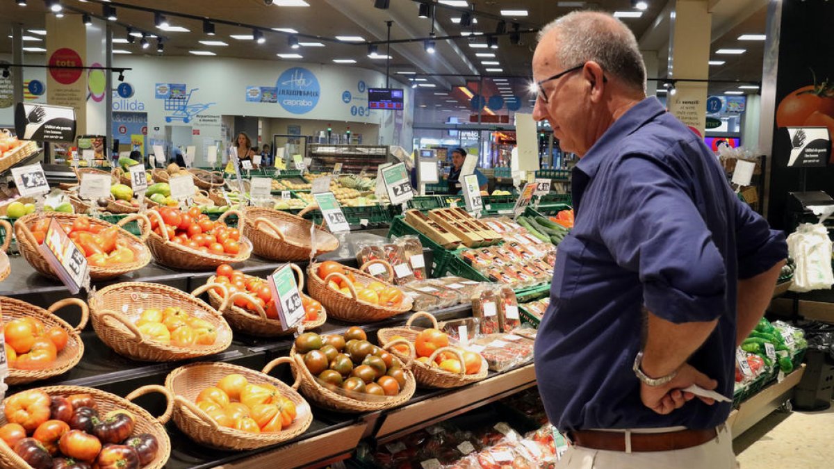 Un home compara els preus de la verdura en un supermercat de Barcelona.