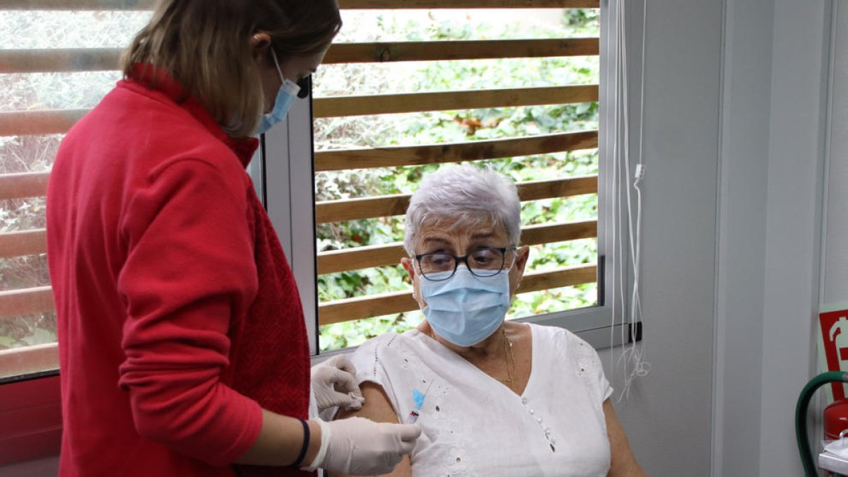 Una professional sanitària prepara el braç de la pacient abans de vacunar-la.