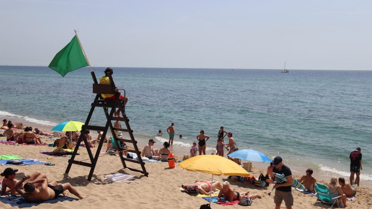 Un socorrista vigila a los bañistas que llenan la playa del Puente de Botifarreta de Badalona.