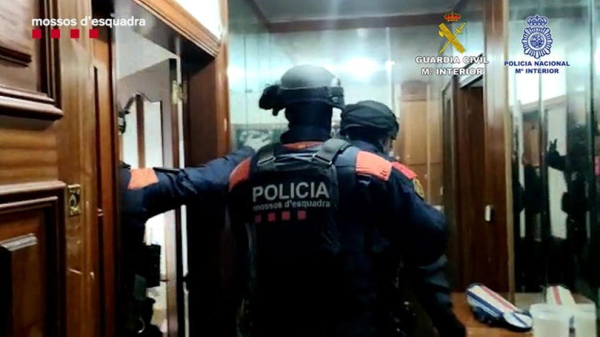 Agentes de los Mossos d'Esquadra entran en un domicilio de los detenidos.