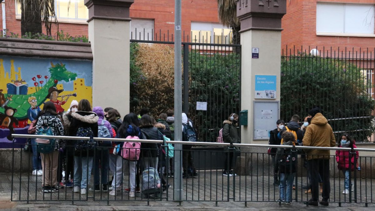 Pla general de l'Escola de les Aigües, amb pares i alumnes esperant a la porta.