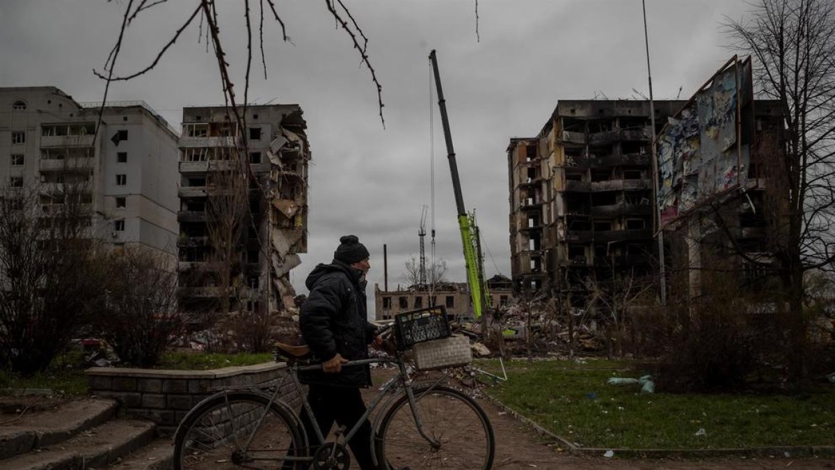 Un hombre camina con su bicicleta frente a un edificio que sufrió daños tras un ataque con artillería pesada, hoy, en Borodianka (Ucrania