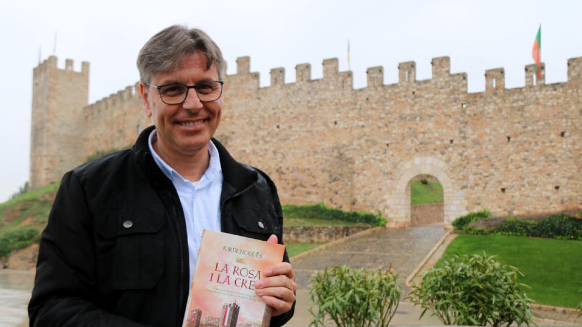 L'escriptor Jordi Nogués subjectant la seva nova novel·la 'La rosa i la creu' davant les muralles de Montblanc.