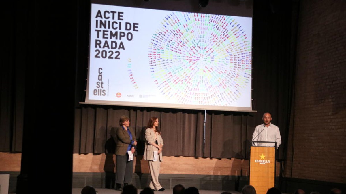 El president de la CCCC, Joan Ibarra, durant la seva intervenció en l'acte d'inici de temporada 2022 del món casteller, amb les dues conductores de l'acte, Mireia Segú i Leticia Dolera, a la sala d'actes de l'Antiga Fàbrica Damm