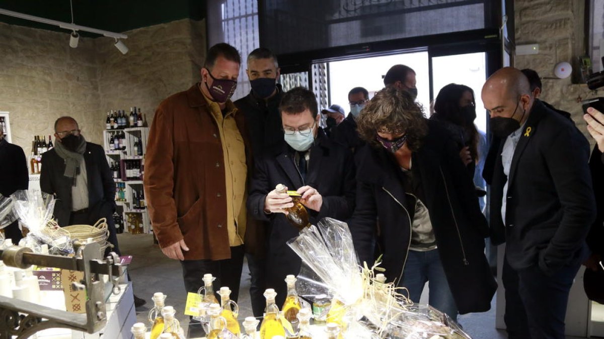 El president de la Generalitat, Pere Aragonès, i la consellera d'Acció Climàtica, Teresa Jordà, miren ampolles d'oli durant una visita a l'Agrobotiga de la Cooperativa d'Arbeca.