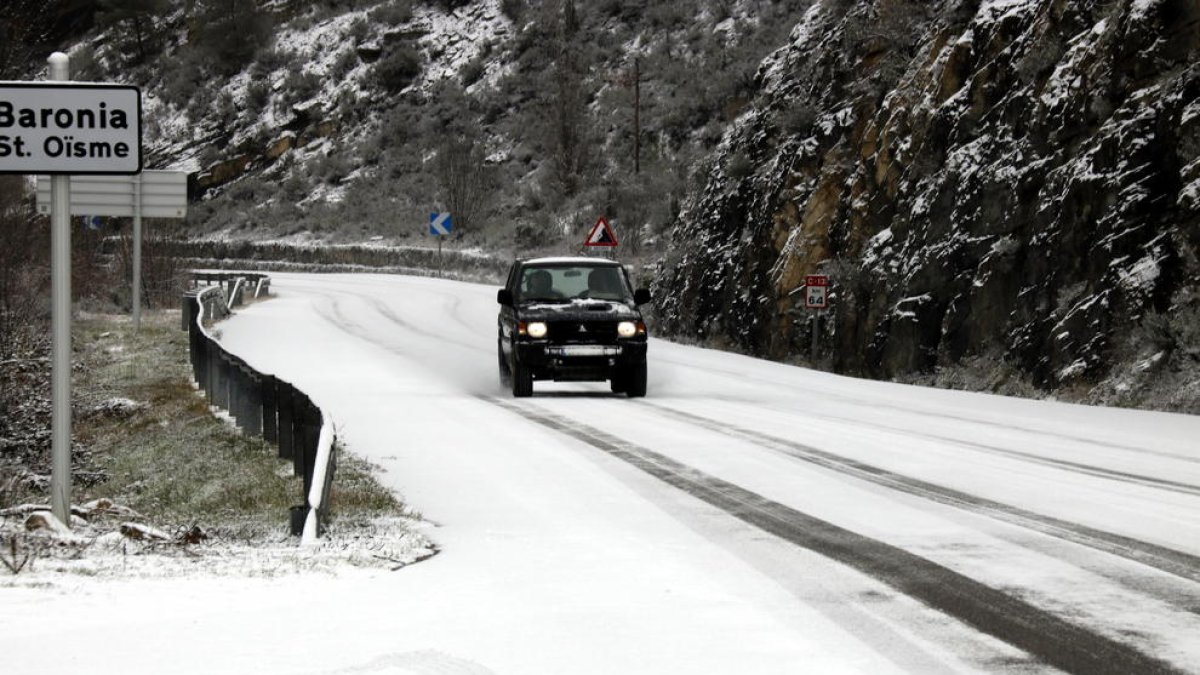 Un cotxe circulant per una carretera nevada.