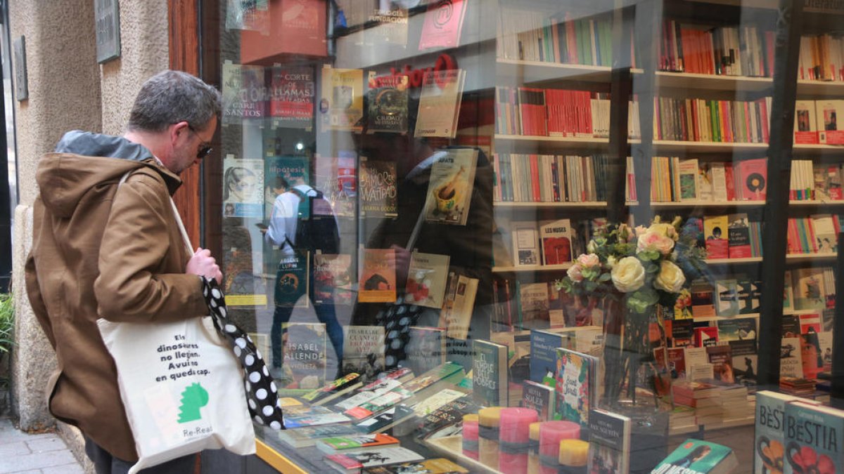 Un hombre mira el escaparate de una librería de Reus el día previo a la Diada de Sant Jordi.