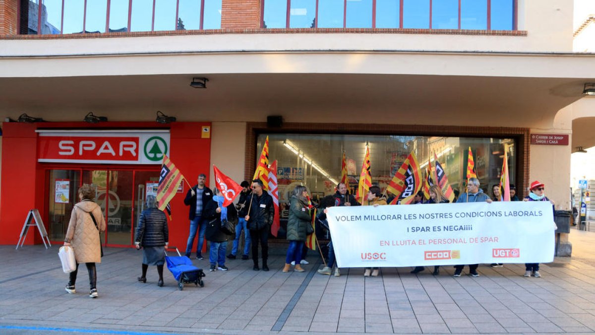 Dues dones entren en un supermercat Spar a Reus, mentre una vintena de treballadors protesten.