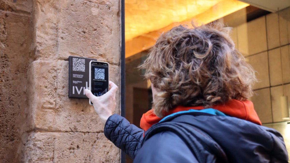 Una persona escanejant el QR de la nova placa instal·lada a l'exterior de la joieria 'Personal' de Tarragona.