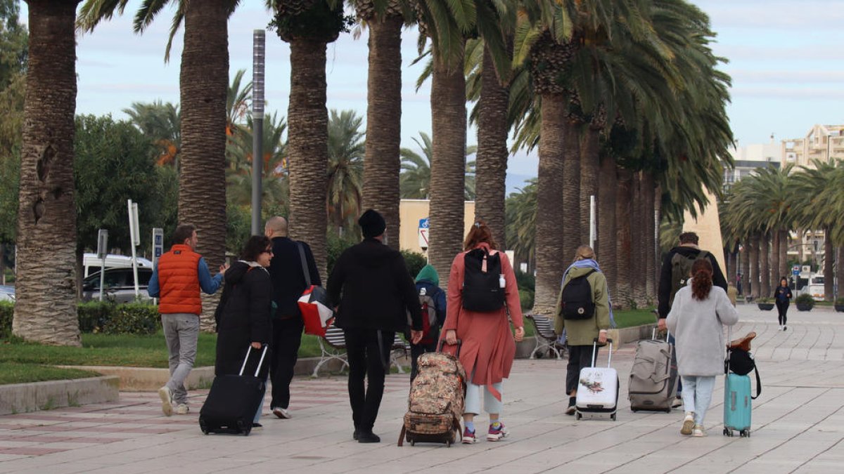 Un grup de persones amb maletes caminant pel passeig Jaume I de Salou.