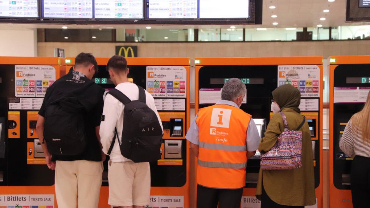 Varias personas en las máquinas de autoventa de Cercanías de la estación de Sants.